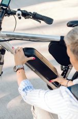 E-Bike-Akku defekt, Was du tun kannst, wenn die Batterie schwächelt Eine Person kniet vor ihrem E-Bike mit den Händen am Akku, um diesen abzunehmen.