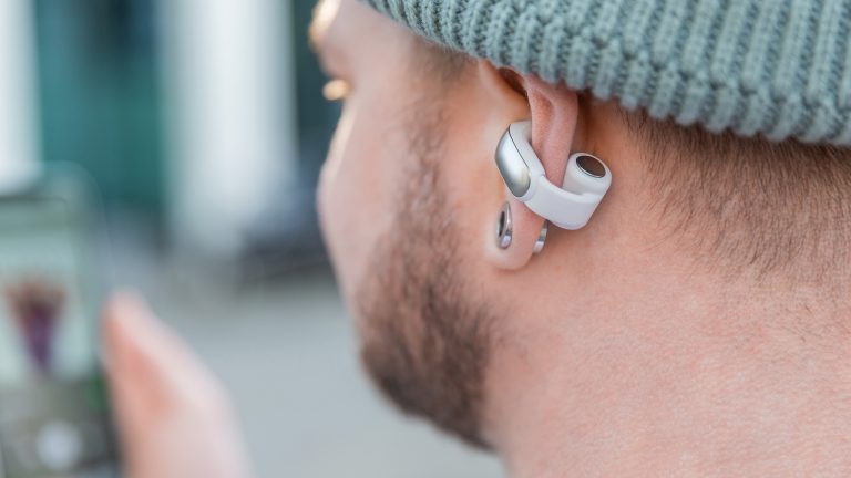 Eine Person tr&auml;gt die Bose Ultra Open Earbuds an ihrem linken Ohr.