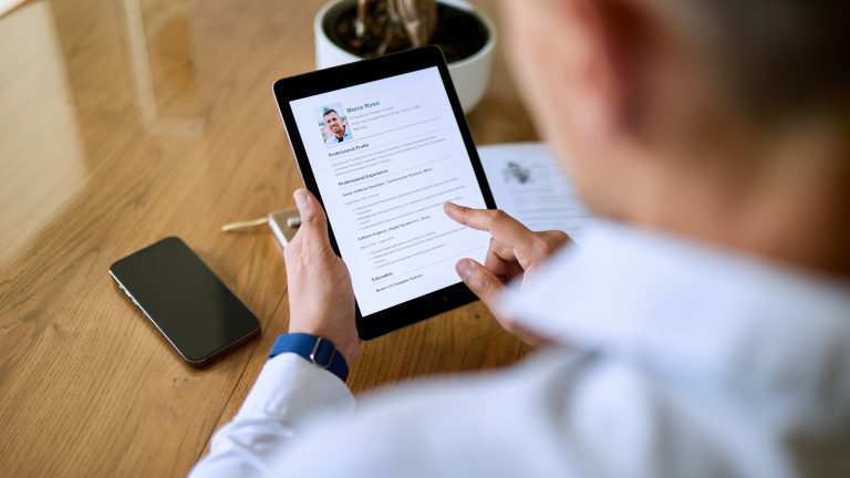 Lebenslauf in Word erstellen, So funktioniert es Eine Person schaut auf ein Tablet, auf dem ein Lebenslauf von ihr zu sehen ist.