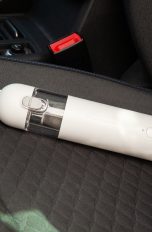 Der Xiaomi Mi Vacuum Cleaner Mini liegt auf einem Autositz mit Stoff-Bezug.