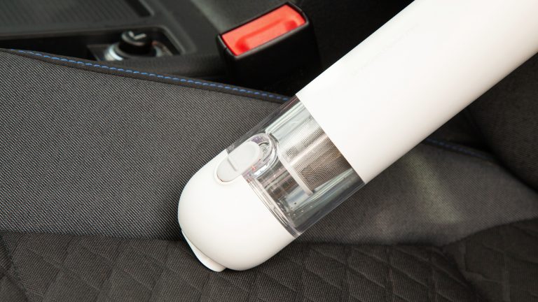 Der Xiaomi Mi Vacuum Cleaner Mini saugt entlang der L&auml;ngsnaht auf der Sitzfl&auml;che eines Autositzes.
