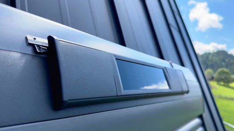 Smarte Rollladensteuerung, Was es ist und was du wissen solltest Bild von einem Solarpanel, das an einem Rollladenkasten angebracht ist.