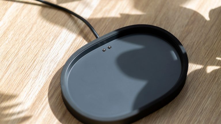 Ansicht der Ladeschale von einem schwarzen Sonos Play, die auf einem Schreibstisch aus Holz liegt.