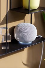 Google Home Speaker, Lautsprecher mit Gemini ausprobiert Ein Google Home Speaker in Weiß steht auf einem schwarzen Regal.