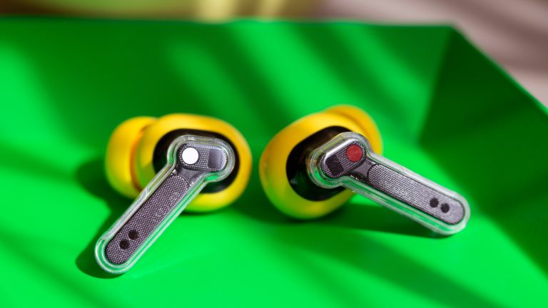 Nahaufnahme der Nothing Ear (a), mit gut zu sehenden, transparenten Stielen, die in einer gr&uuml;nen Schale liegen.