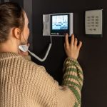 Eine Person bedient in ihrem Zuhause eine Video-Gegensprechanlage.