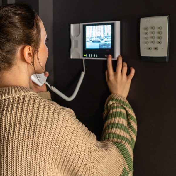 Eine Person bedient in ihrem Zuhause eine Video-Gegensprechanlage.
