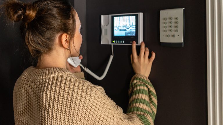 Eine Person bedient in ihrem Zuhause eine Video-Gegensprechanlage.