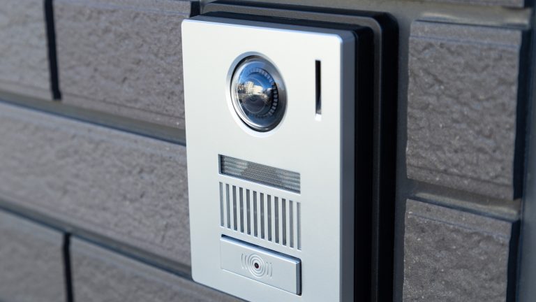 Eine Outdoor-Kamera ist an der Au&szlig;enwand eines Wohnhauses neben der Haust&uuml;r montiert.