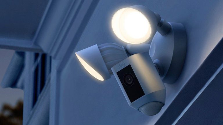 Smarte Überwachungskameras, 6 Geräte für Haus und Grundstück Eine Ring Cam Floodlight hängt an der Außenfassade eines Hauses.