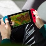 Eine Person sitzt auf einem Sessel und spielt auf einer Nintendo Switch.