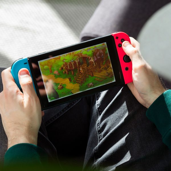 Eine Person sitzt auf einem Sessel und spielt auf einer Nintendo Switch.