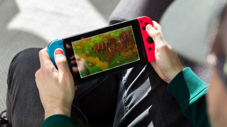 Eine Person sitzt auf einem Sessel und spielt auf einer Nintendo Switch.