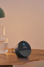 KI im Smarthome, Mit Gemini Home und Alexa+ das Zuhause steuern Ein Amazon Echo Spot steht auf einem Nachttisch neben einem gemachten Bett.
