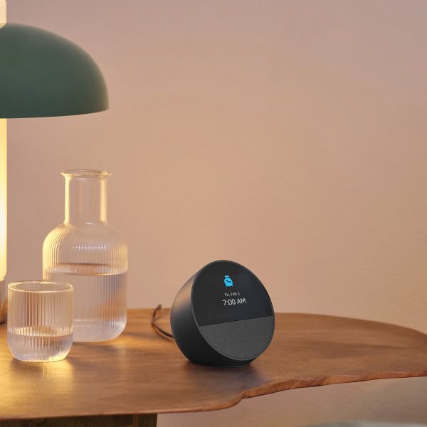 Ein Amazon Echo Spot steht auf einem Nachttisch neben einem gemachten Bett.