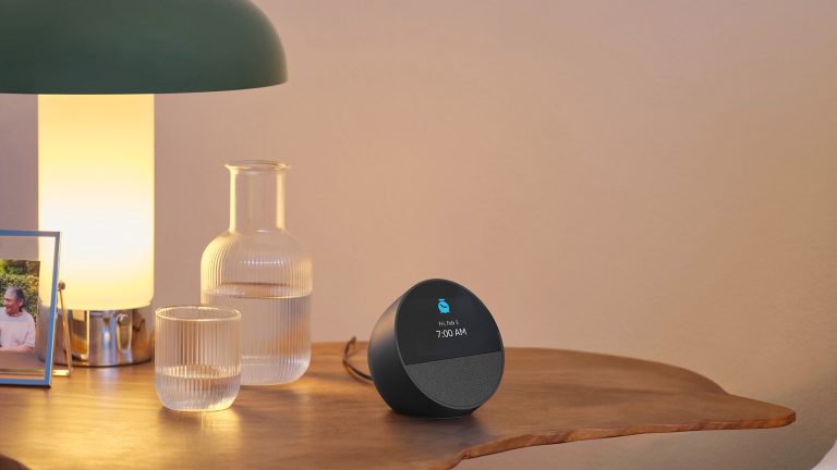 Ein Amazon Echo Spot steht auf einem Nachttisch neben einem gemachten Bett.