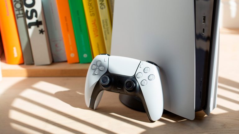 PlayStation Family-App, Kindersicherung und mehr nutzen Ein weißer Dualsense-Controller lehnt an einer PS5 Digital Edition mit weißen Sideplates.