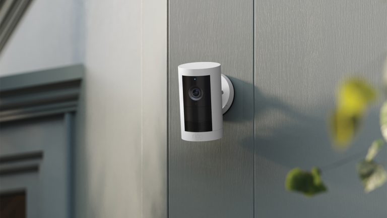 KI im Smarthome, Mit Gemini Home und Alexa+ das Zuhause steuern Eine Ring Outdoor Camera Plus in Nahaufnahme an der Seite eines Hauses.