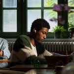 Eine Person sitzt in einem Caf&eacute;, um sie herum sprechen Leute. Sie tr&auml;gt die AirPods 5 und scheint in Ruhe arbeiten zu k&ouml;nnen.