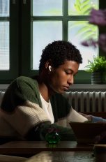 AirPods 5, Apples bisher attraktivste Kopfhörer Eine Person sitzt in einem Café, um sie herum sprechen Leute. Sie trägt die AirPods 5 und scheint in Ruhe arbeiten zu können.