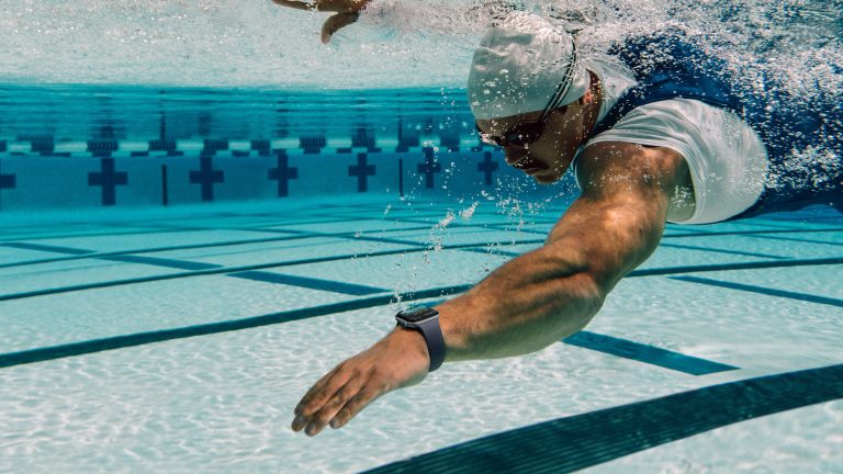 Eine Person krault im Wasser. An der linken Hand trägt sie eine Apple Watch 12.