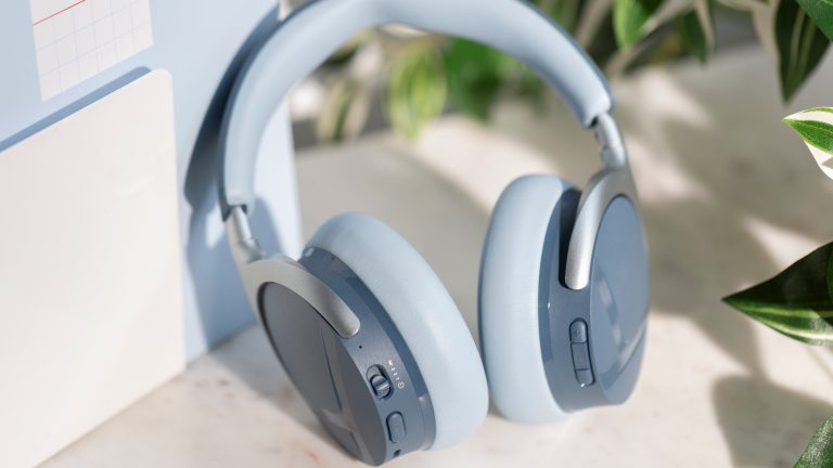 Die Aventho Y von Beyerdynamic in Blau lehnen an einem Notizbuch. Zu sehen sind alle physischen Kn&ouml;pfe der Kopfh&ouml;rer.
