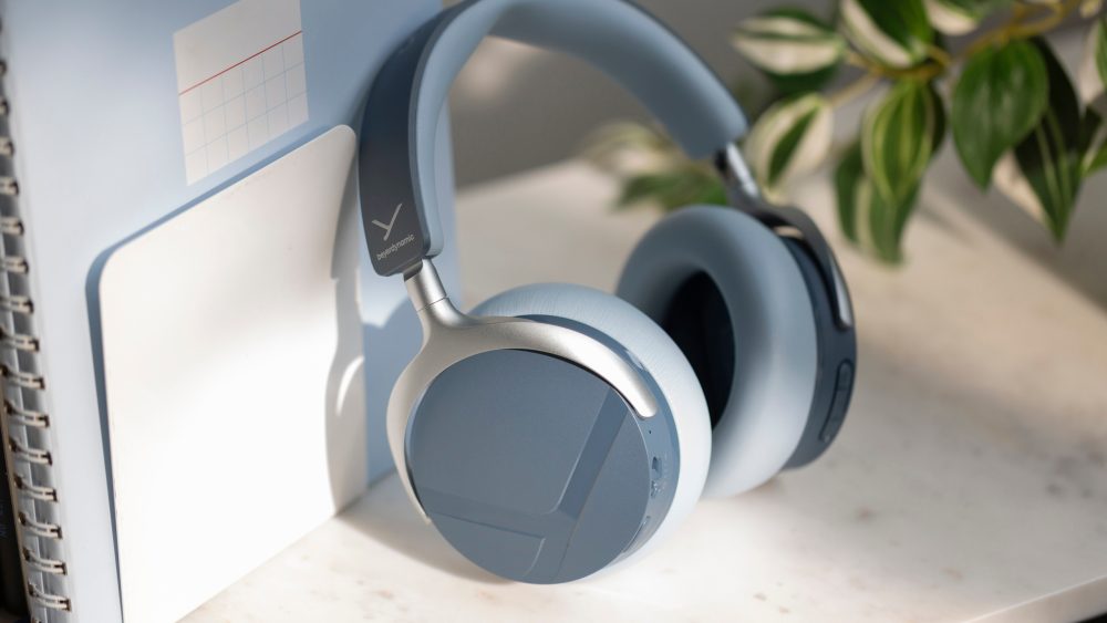 Die Beyerdynamic Aventho Y in Blau stehen angelehnt an ein Notizbuch auf einem Tisch.