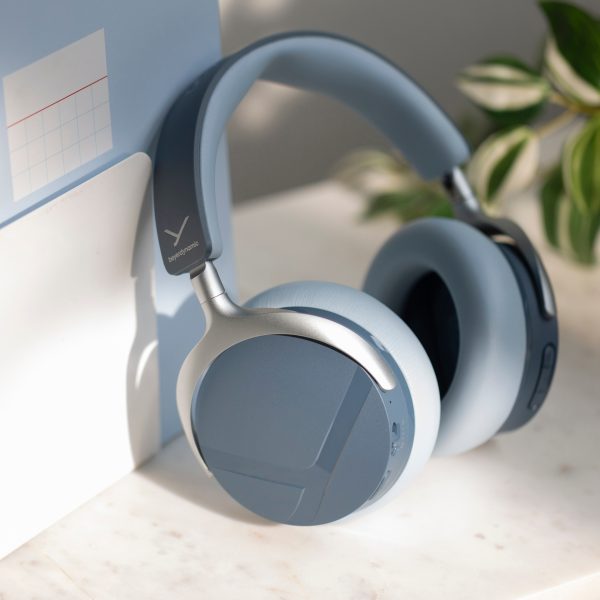 Die Beyerdynamic Aventho Y in Blau stehen angelehnt an ein Notizbuch auf einem Tisch.