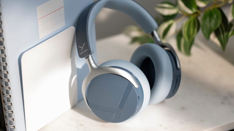 Die Beyerdynamic Aventho Y in Blau stehen angelehnt an ein Notizbuch auf einem Tisch.