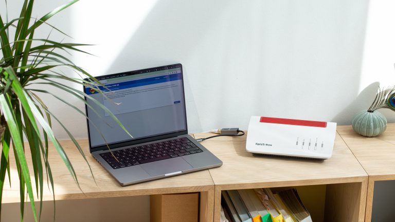 in Laptop steht neben einer Fritzbox auf einem halbhohen Regal.