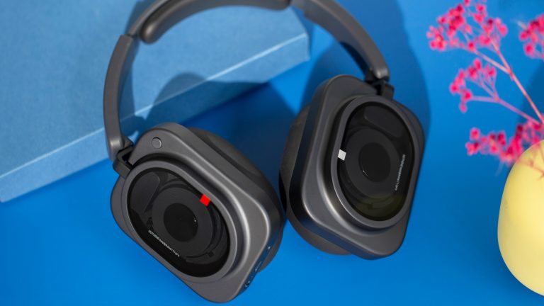 Blick auf die Nothing Headphone (1) Pro, die leicht eingeklappt auf einem blauen Untergrund liegen.