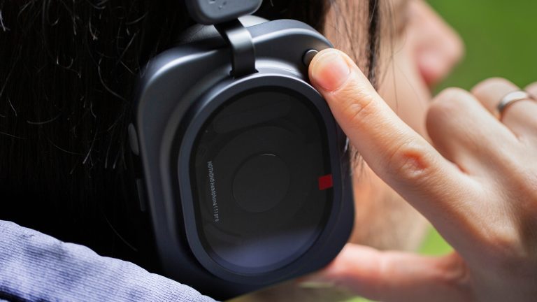 Nothing Headphone (1) Pro, Premium-Kopfhörer mit cleveren Studio-Ideen im Praxistest Eine Person trägt die Nothing Headphone (1) Pro und fasst mit dem Zeigefänger an den außenliegenden Knopf.