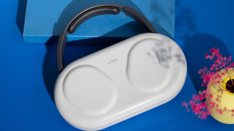 Die Nothing Headphone (1) Pro in ihrem wei&szlig;en Hardcase auf einem blauen Untergrund.