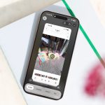 Ein iPhone liegt auf einem wei&szlig;en Notizbuch. Auf dem Bildschirm ist ein Screenshot von Outdoor-M&ouml;beln zu sehen. Sie sind markiert f&uuml;r eine visuelle Suche.