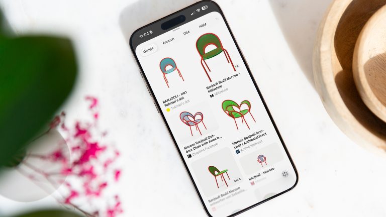 Highlight to Search, So nutzt du die Apple-KI-Funktion Ein iPhone liegt auf einem weißen Tisch. Auf dem Bildschirm sind bunte Stühle verschiedener Onlineshops zu sehen.