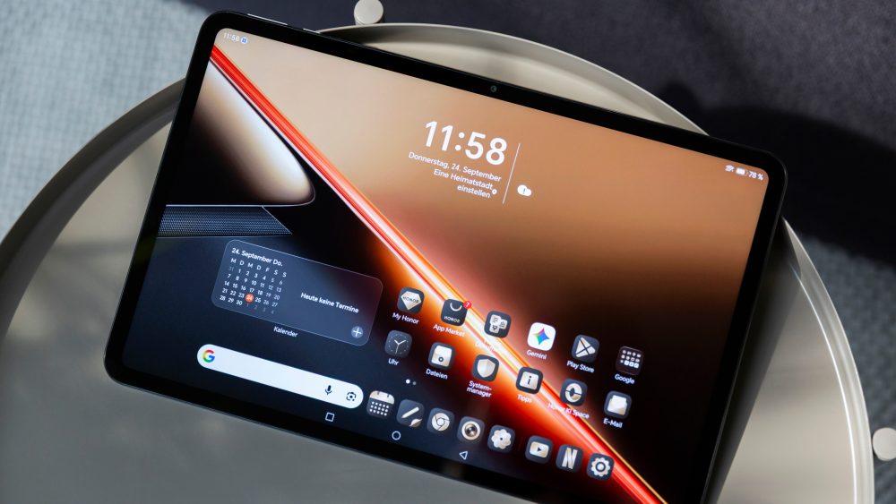 Ein Honor Pad X9 Max liegt mit angeschaltetem Display, auf dem der Homescreen zu sehen ist, auf einem Beistelltisch.