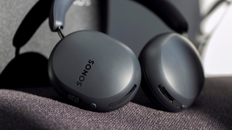 Die Sonos Ace in Schwarz liegen, leicht eingedreht, auf einem Sofa.