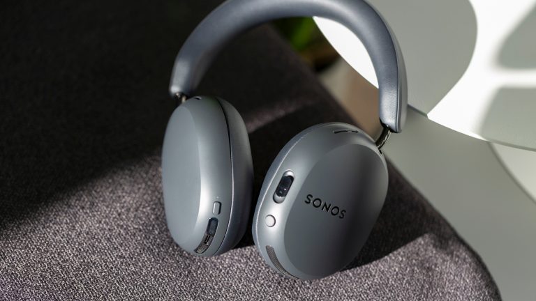 Die Sonos Ace Ultra in Schwarz liegen an einen Beistelltisch gelehnt auf einem Sessel.