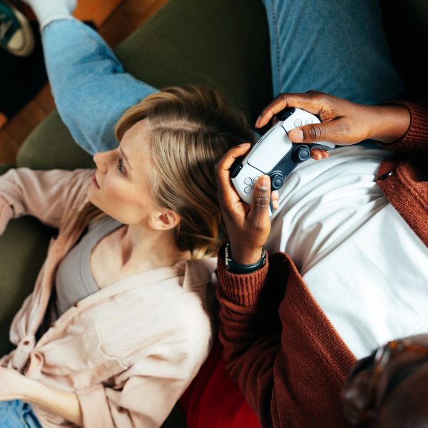 Zwei Personen liegen gemütlich auf einem Sofa und halten Controller in der Hand.