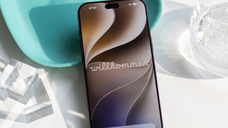 Ein iPhone 18 Pro Max liegt an eine Schale gelehnt auf einem Tisch. Auf dem Display ist der Willkommens-Bildschirm zu sehen.