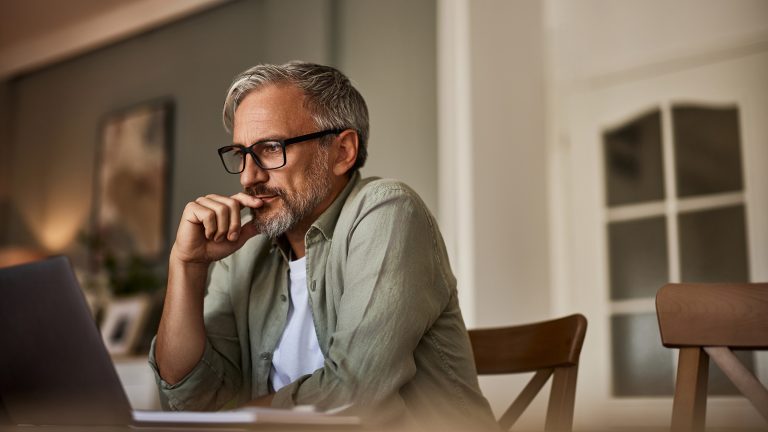 Eine Person sitzt an einem Tisch und arbeitet an einem Notebook