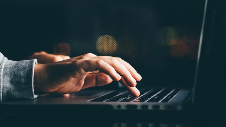 Hände bedienen die Tastatur eines Notebooks.